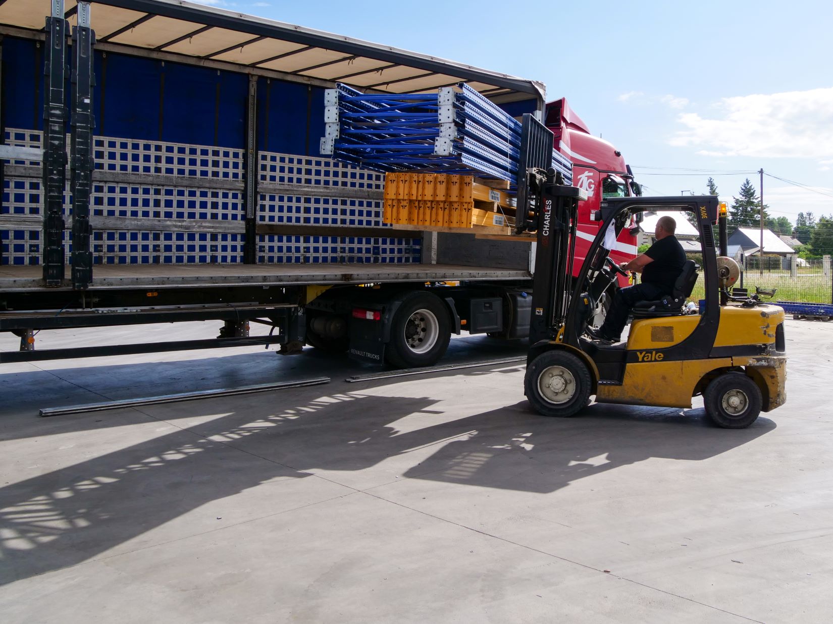 un chariot élévateur charge des rayonnages industriels dans un camion